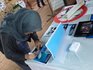 A visitor signing an action commitment sticker at our booth