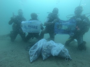 happy divers under the water making a change by cleaning the dive site 