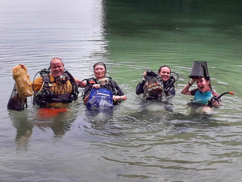 Divers holding mesh bags full of trash