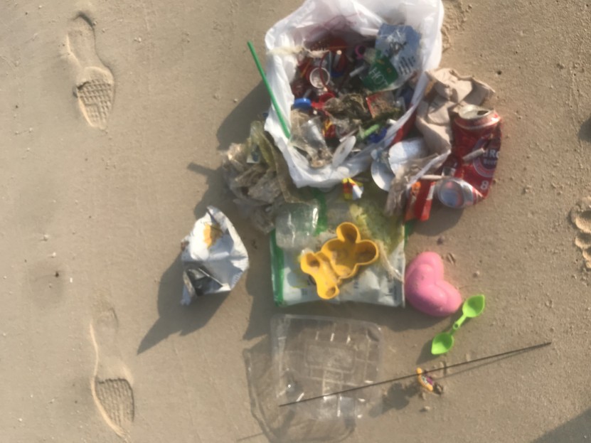 Collect of various pieces of trash, including plastic toys, plastic bottle caps, cigarette butts, styrofoam, plastic, fabric bits, food packages, plastic containers