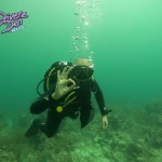 Divemaster Jorge making an OK sign to the camera while swimming over the reef.